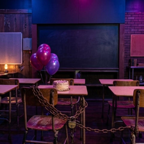 Detention classroom set with old school desks, a birthday cake, balloons and a chained desk